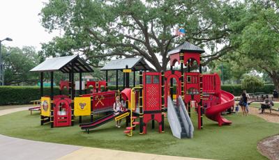 Playground that is custom designed as a fire station with Mom helping child down the slide.