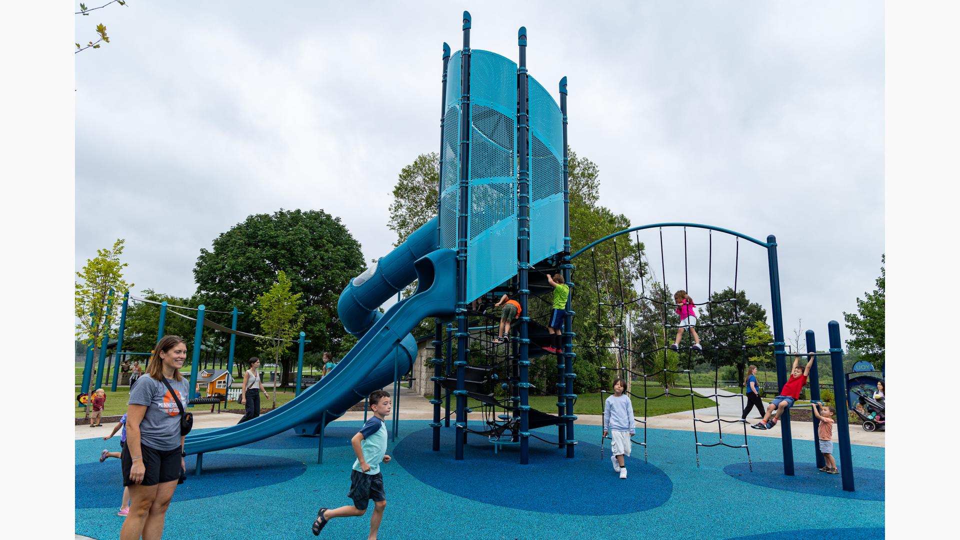 Children play all over a tower structure with many play activities.