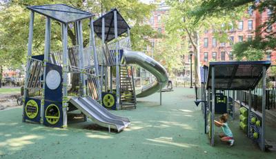 Child plays on learning wall next to Joseph C. Sauer Park playscape