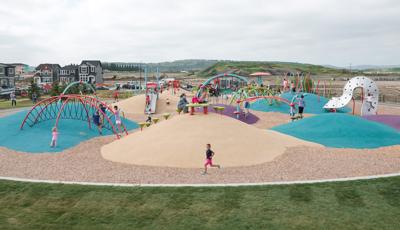 Children play on the uniquely arched and colored climbers of a neighborhood park.