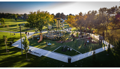 Elevated view of a hexagonal shaped playground play area with a large main tower with stainless steel slide and a secondary large figure eight shaped climbing structure.