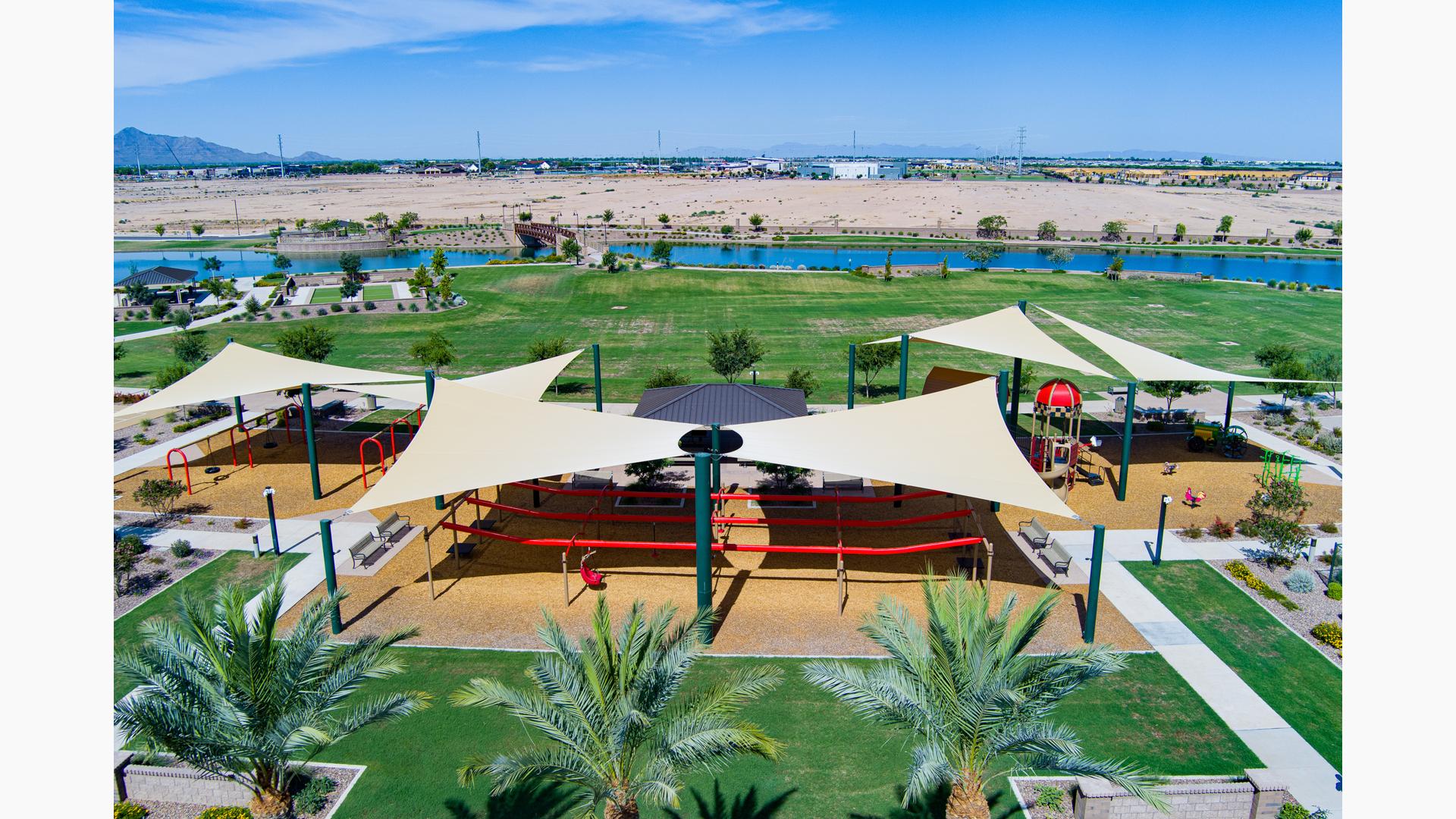 Elevated view of a park playground with large shade sails providing shade over the play structures.