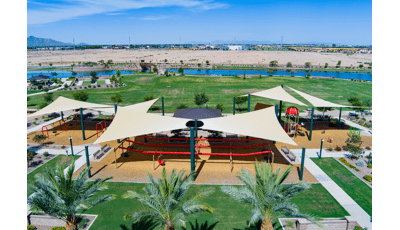Elevated view of a park playground with large shade sails providing shade over the play structures.
