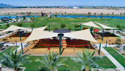 Elevated view of a park playground with large shade sails providing shade over the play structures.
