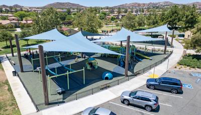 Elevated view of a large enclosed play area with large blue shade sails covering almost all of the playground area.