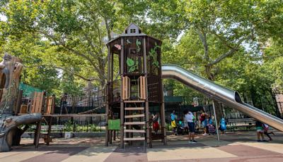 Adutls stand with their babies under nature-inspired play structure, while kids walk across the wooden bridge and run around the stainless steel tunnel slide.