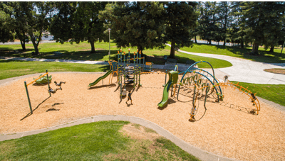 Nielson Park Sacramento, CA featuring a 7-post Netplex® play structure for ages 5-12 linked to an Evos® play system. Nearby a Weevos® play system for toddlers and preschoolers.