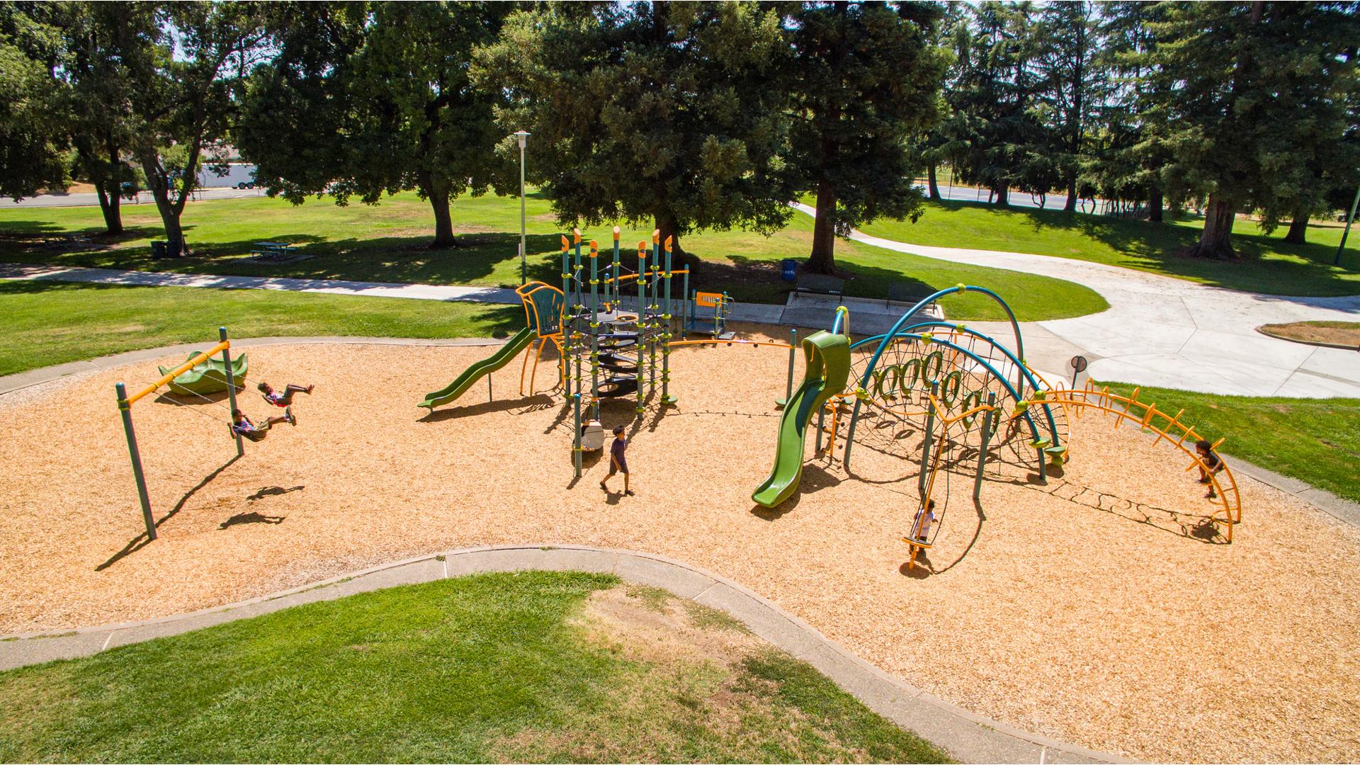 Nielson Park Sacramento, CA featuring a 7-post Netplex® play structure for ages 5-12 linked to an Evos® play system. Nearby a Weevos® play system for toddlers and preschoolers.