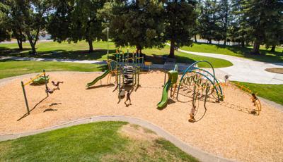 Nielson Park Sacramento, CA featuring a 7-post Netplex® play structure for ages 5-12 linked to an Evos® play system. Nearby a Weevos® play system for toddlers and preschoolers.