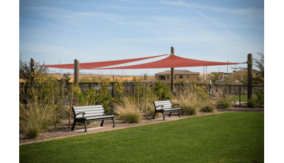 Two benches under two maroon colored shade sails.