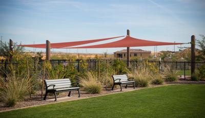 Two benches under two maroon colored shade sails.