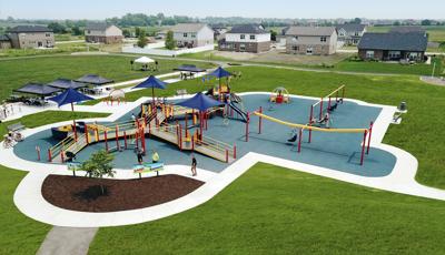 Elevated view of a neighborhood park inclusive play area. The playground is connected by accessible ramps and bridges surrounded by a swing set, zip line, and manual carousel. 