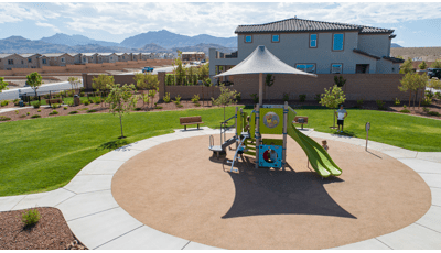 A circular play area has a single play structure with shade in a desert neighborhood setting.
