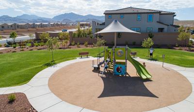 A circular play area has a single play structure with shade in a desert neighborhood setting.
