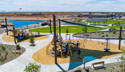 Elevated view of two separate play areas divided by walking paths under large triangular blue shade sails.