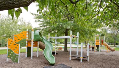 Two PlayBooster® play structures deliver play opportunities for kids ages 2 to 5 and 5 to 12. Playground sits under a full canopy of Oak trees.