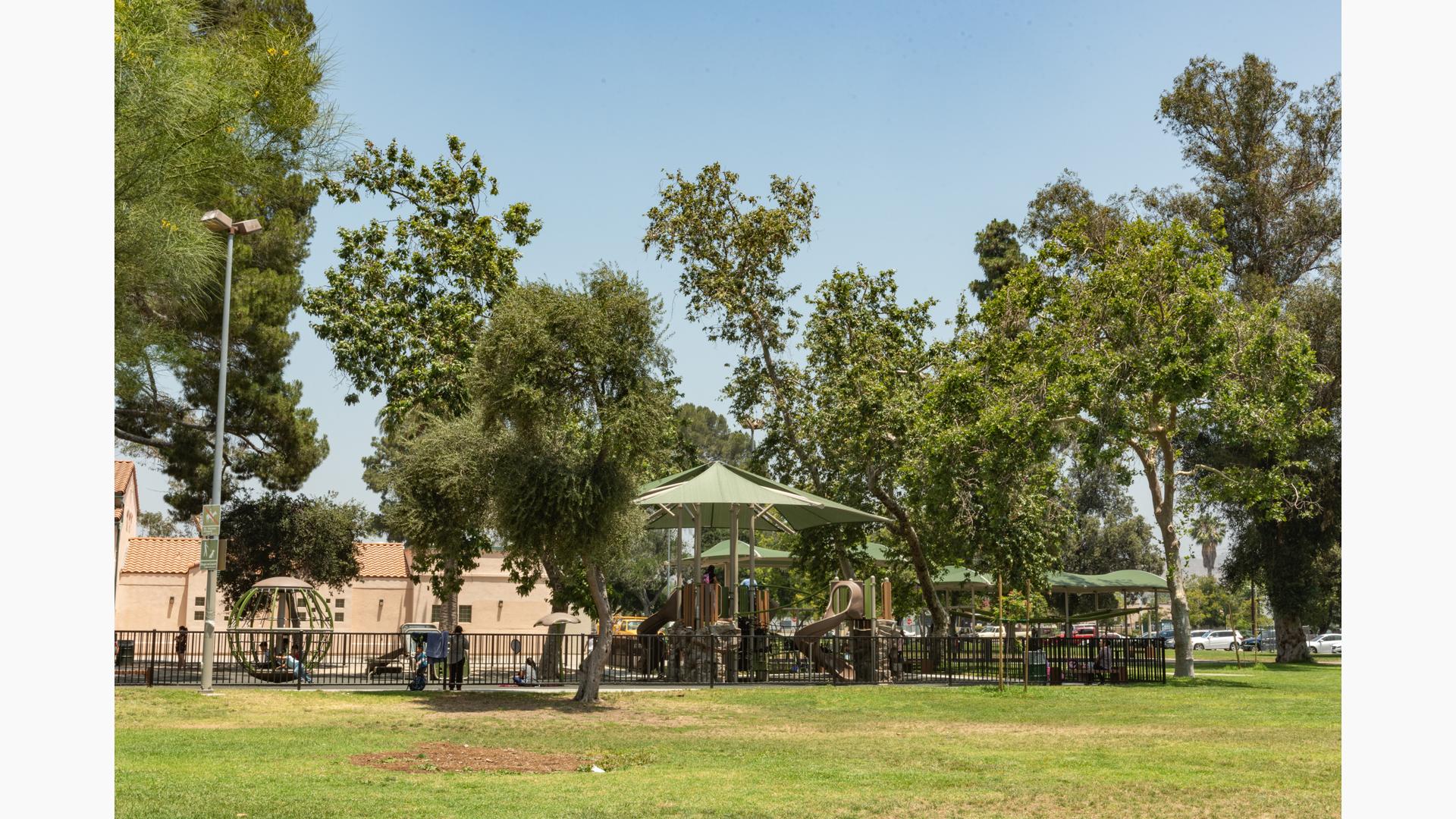 Large trees give a natural canopy to the Sun Valley Rec Center playground. The playground features rock climbers, a double ZipKrooz, and Skyways shade panels in addition to the natural tree shade.