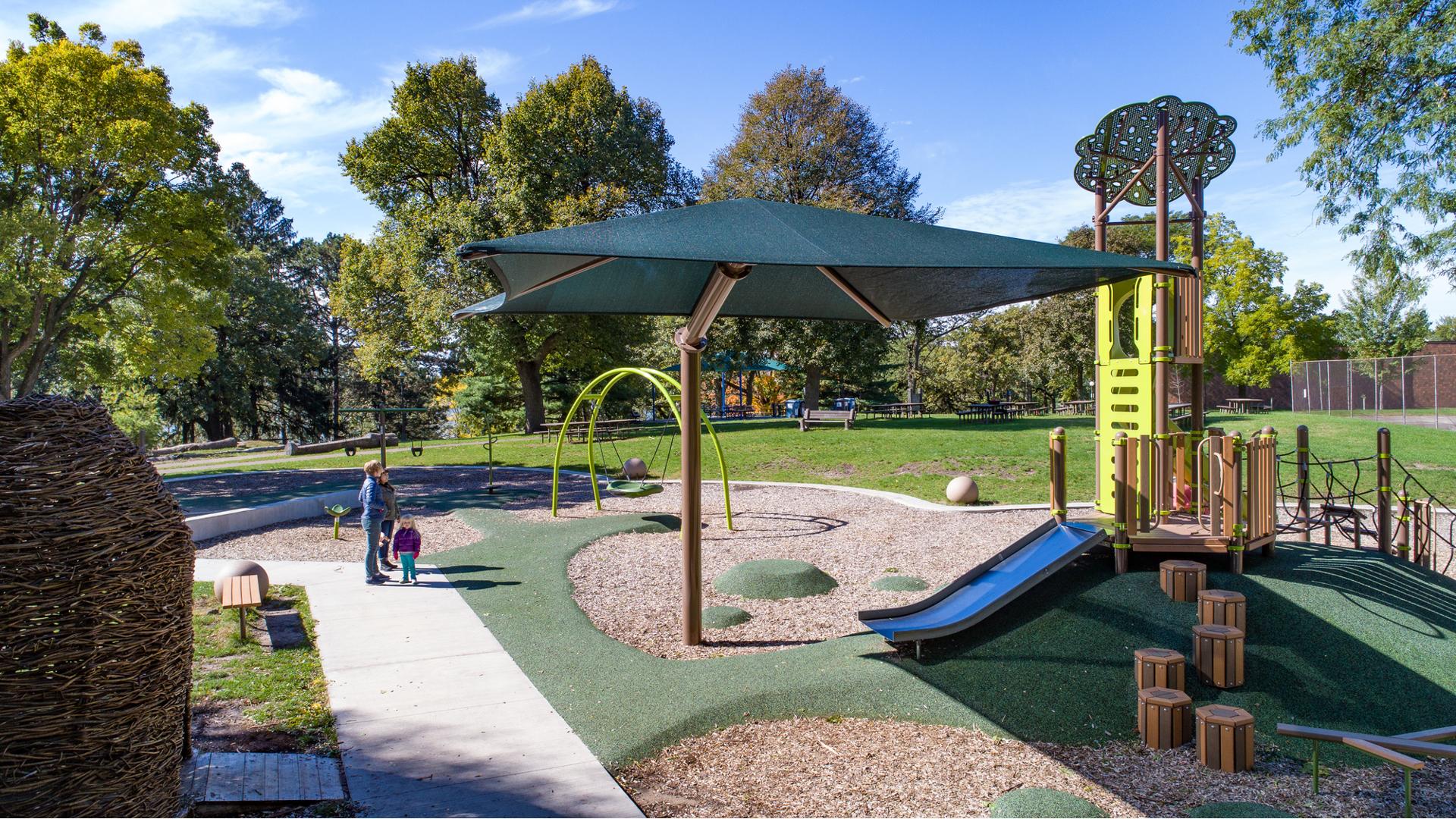 Lake Nokomis Community Center
Minneapolis, MN is a nature-inspired playground featuring a custom climber, custom log steppers and stainless steel slide. The custom SkyWays® shade structure, SlideWinder and custom roofs and tree post toppers carry the natural playground theme throughout.