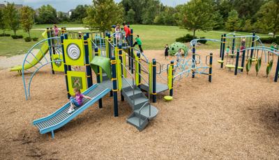 Girls rides down Roller Slide as other kids climb play structure in the background.