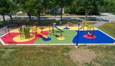 Elevated view of a colorful park playground with slides, spinners, climbers and a bay of swings.