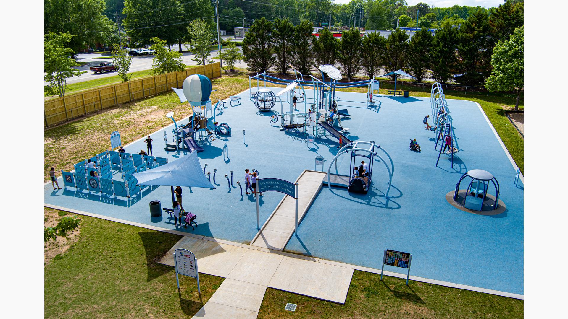 Elevated view of a large inclusive playground with blue safety surfacing. 