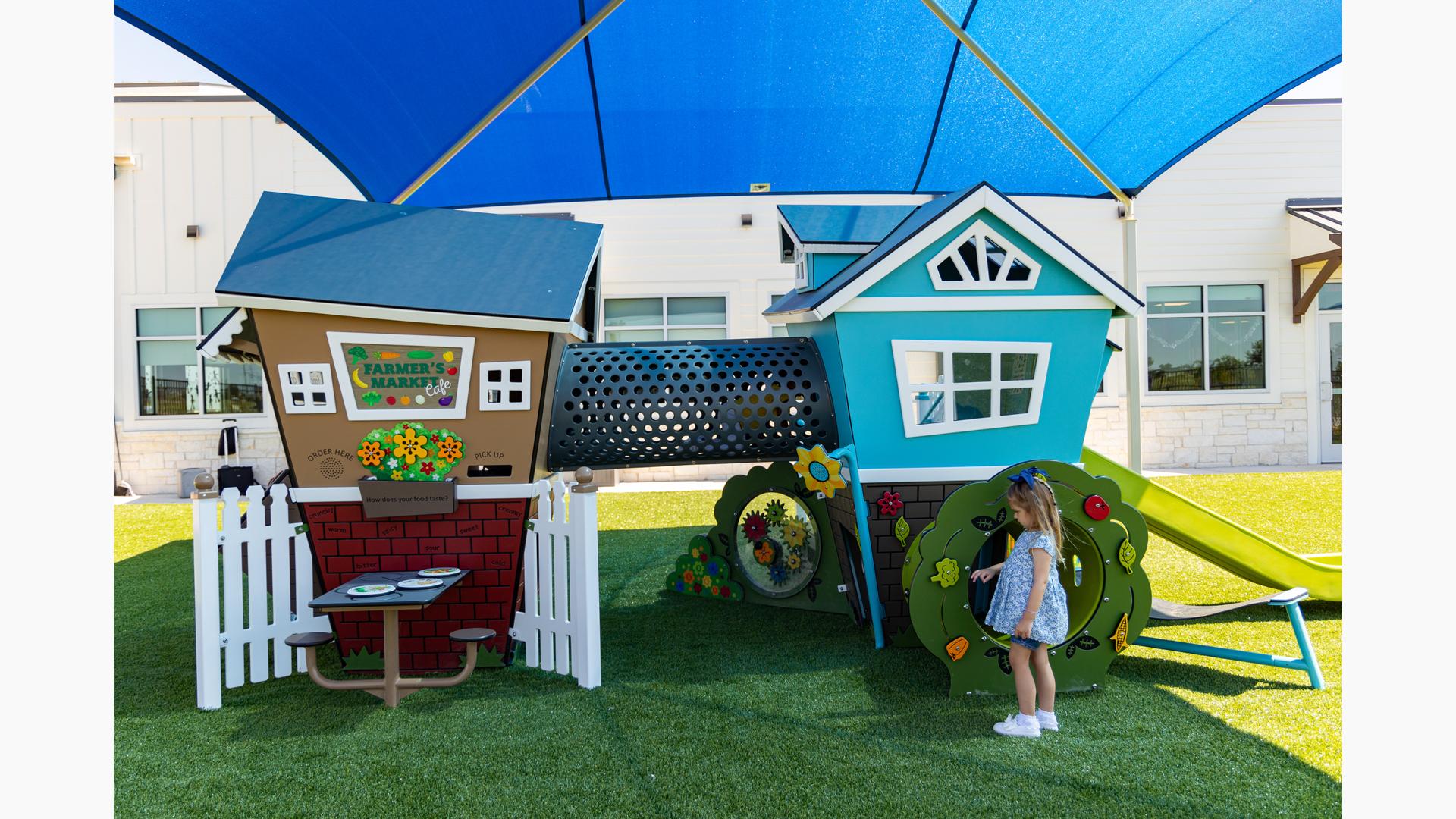 Two small house shaped structures with play panels are connected by a perforated crawl tunnel.