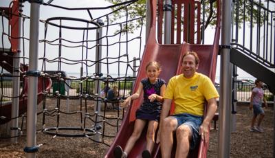 Man and girl ride down slide together