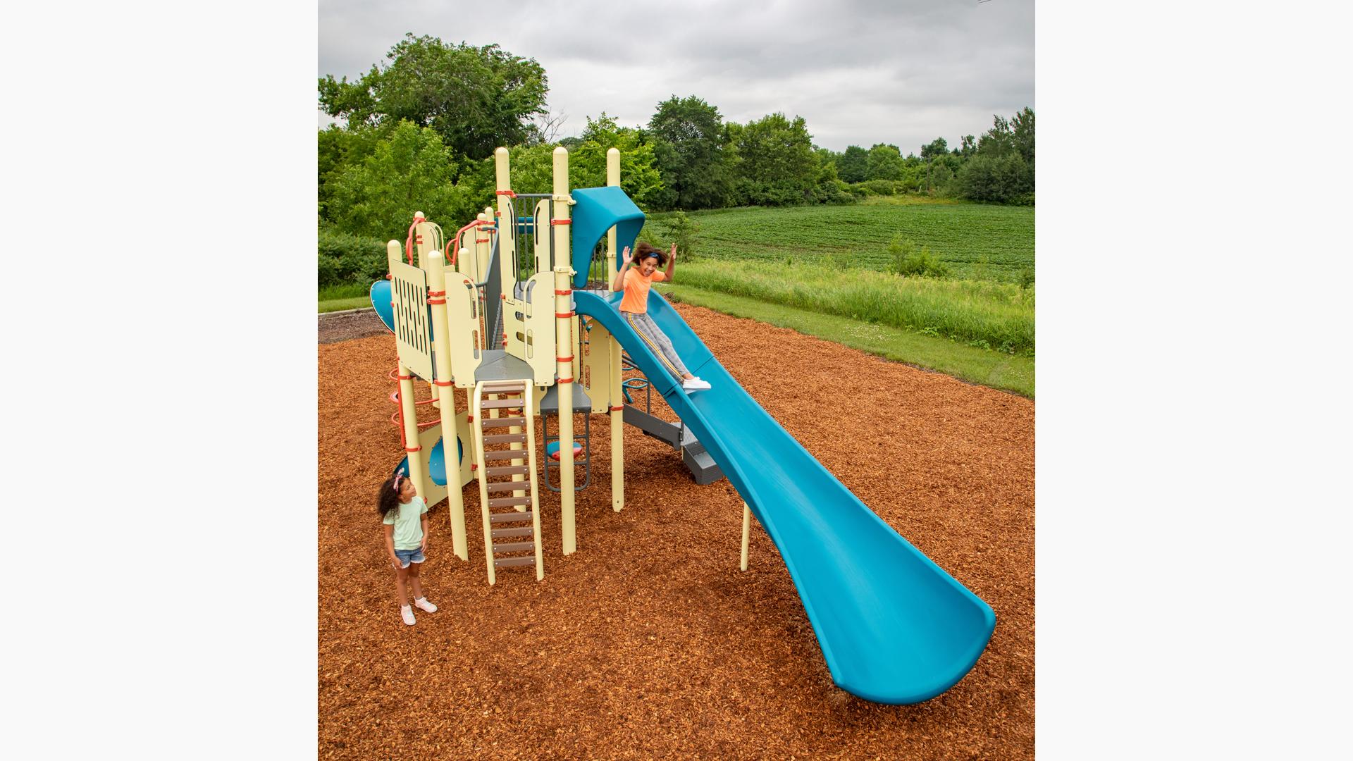 A girl descends a blue Alpine Slide on a yellow PlayBooster playset.