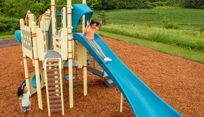 A girl descends a blue Alpine Slide on a yellow PlayBooster playset.