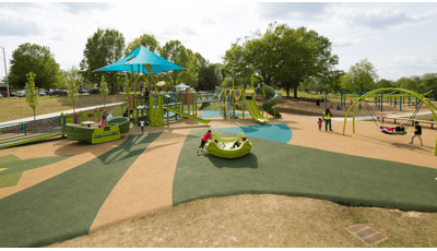 Three kids play in an Omnispin, while a mother takes her daughter for a walk. Two boys play on an Oodle Swing.