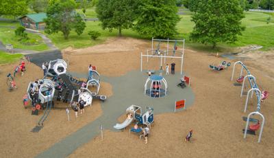 Elevated view of a circular play area with main play structure with swing set and other freestanding play activities.