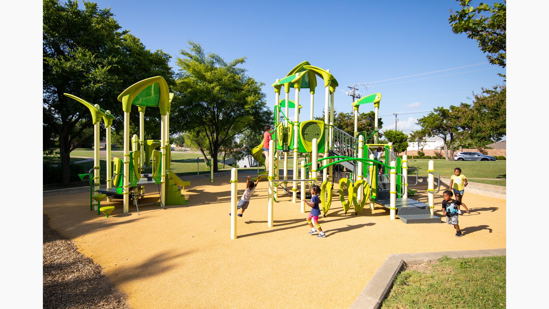 Children running and playing around two play structures with bright green climbers and slides with unique triangular shaped roofs.