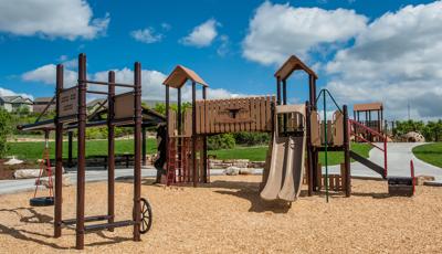 Cattle ranch themed PlayBooster playscape with tire swing and dud ranch style signage.