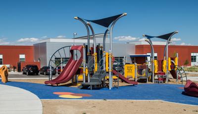 Red, silver and yellow playground in front of red and silver building. 