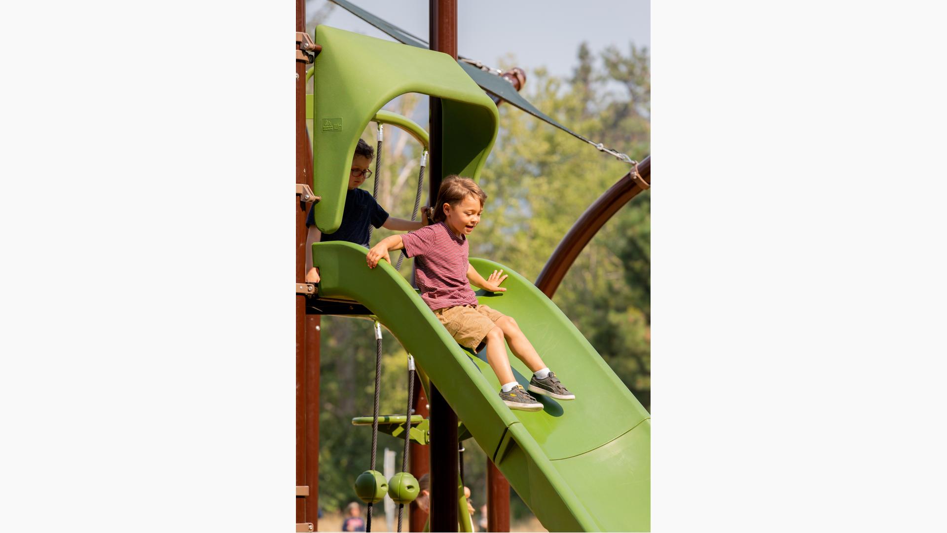 Boy riding down Play Booster slide