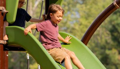 Boy riding down Play Booster slide