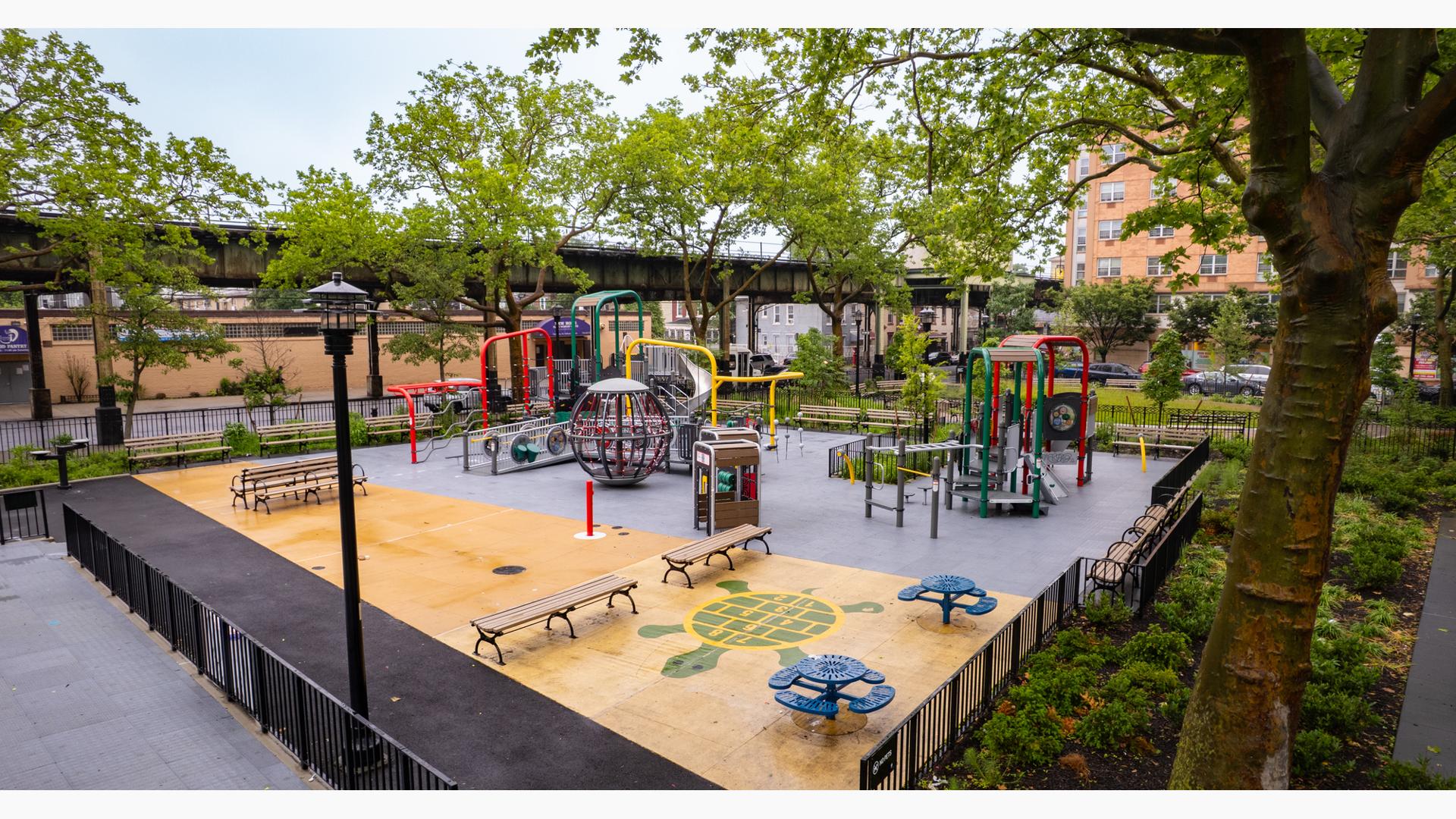 A brightly colored park playground amongst city buildings.