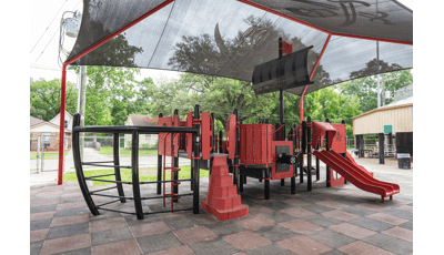Custom pirate ship designed playground sitting under black skull with cross swords shade canopy.