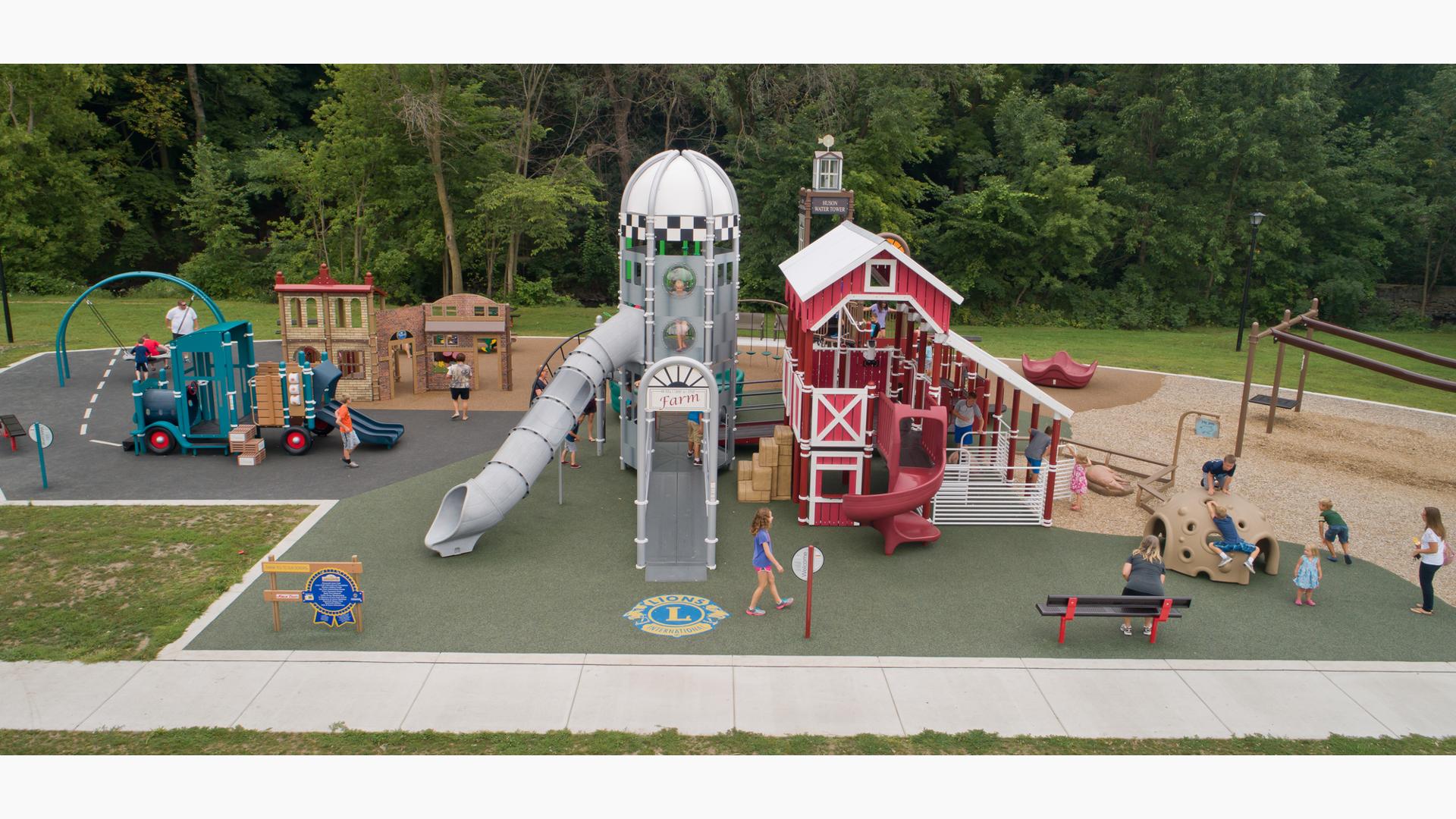 Custom farm-themed PlayBooster playground has two towers and a pickup truck-shaped slide for kids to ride down or climb on.