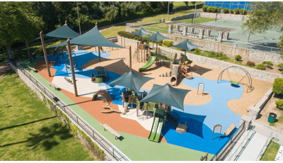 A fenced in play area next to outdoor basketball courts provides two play structures and other freestanding play activities for all ages of children.