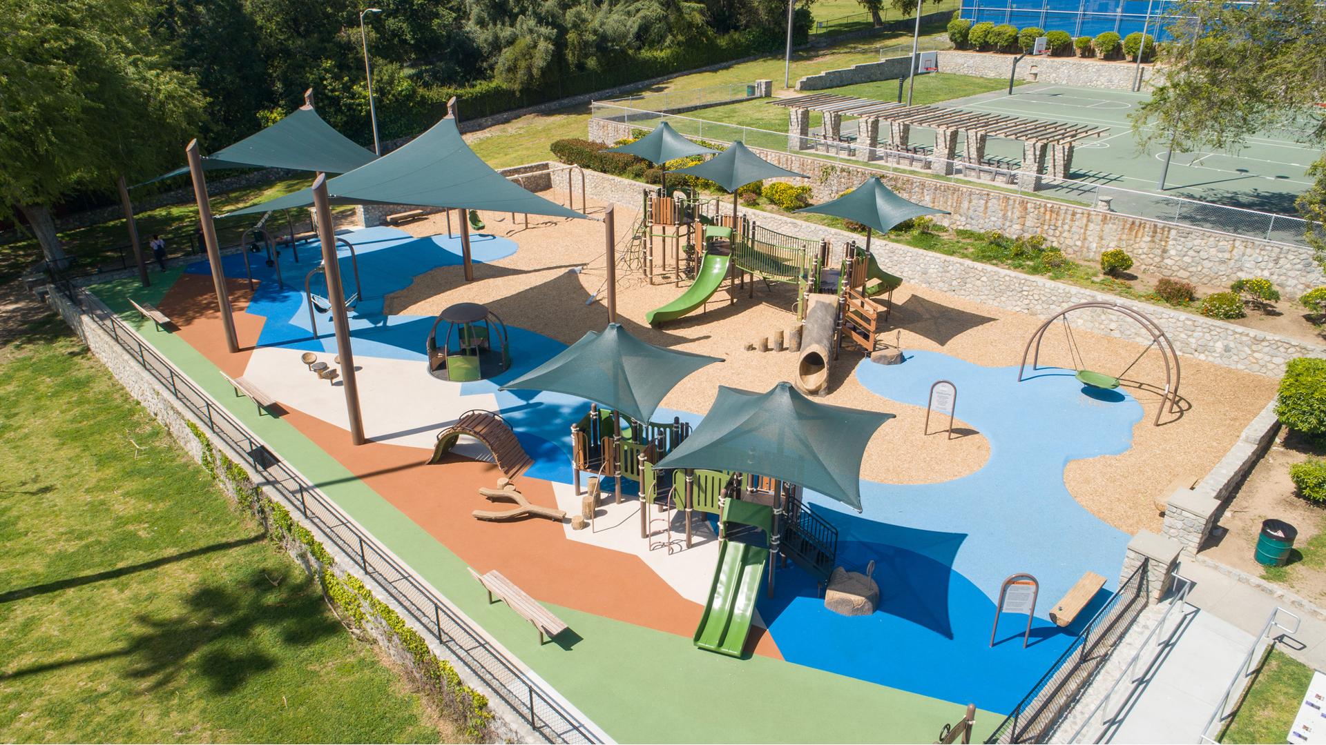 A fenced in play area next to outdoor basketball courts provides two play structures and other freestanding play activities for all ages of children.