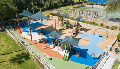 A fenced in play area next to outdoor basketball courts provides two play structures and other freestanding play activities for all ages of children.