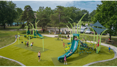 Elevated view of a park play area with two brightly green colored play structures and a set of swings.