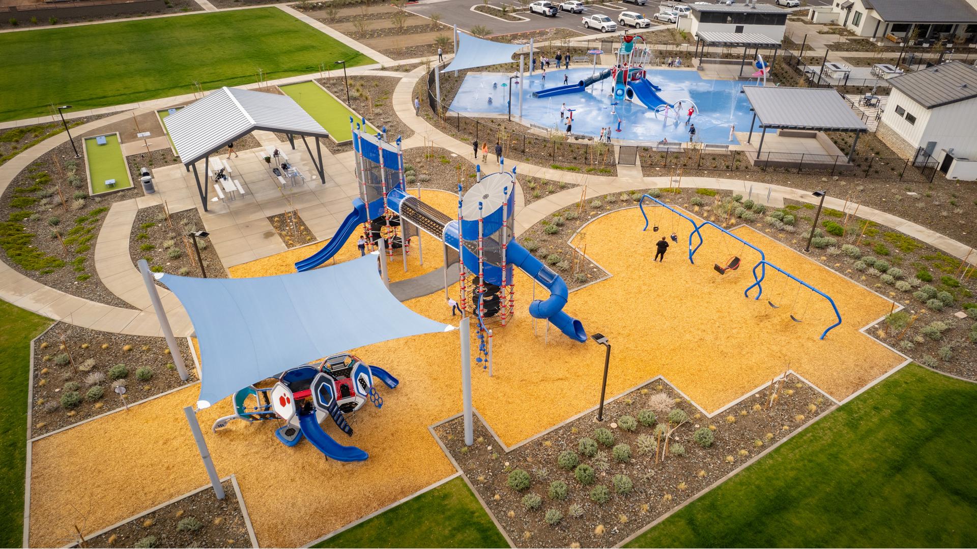 Elevated view of a playground play area with a covered picnic area and near by splash pad.