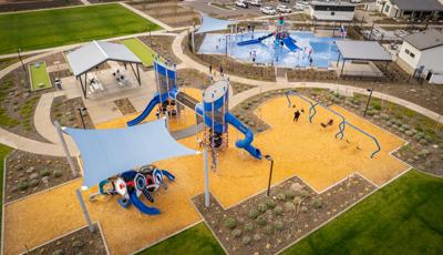 Elevated view of a playground play area with a covered picnic area and near by splash pad.