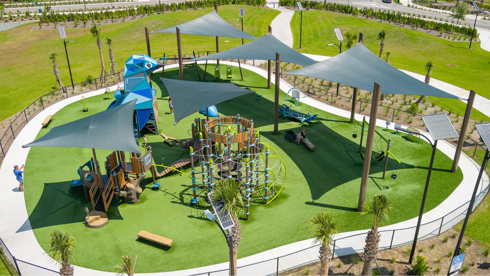 Elevated view of large shade sails covering a playground with a large custom bluebird shape play structure.