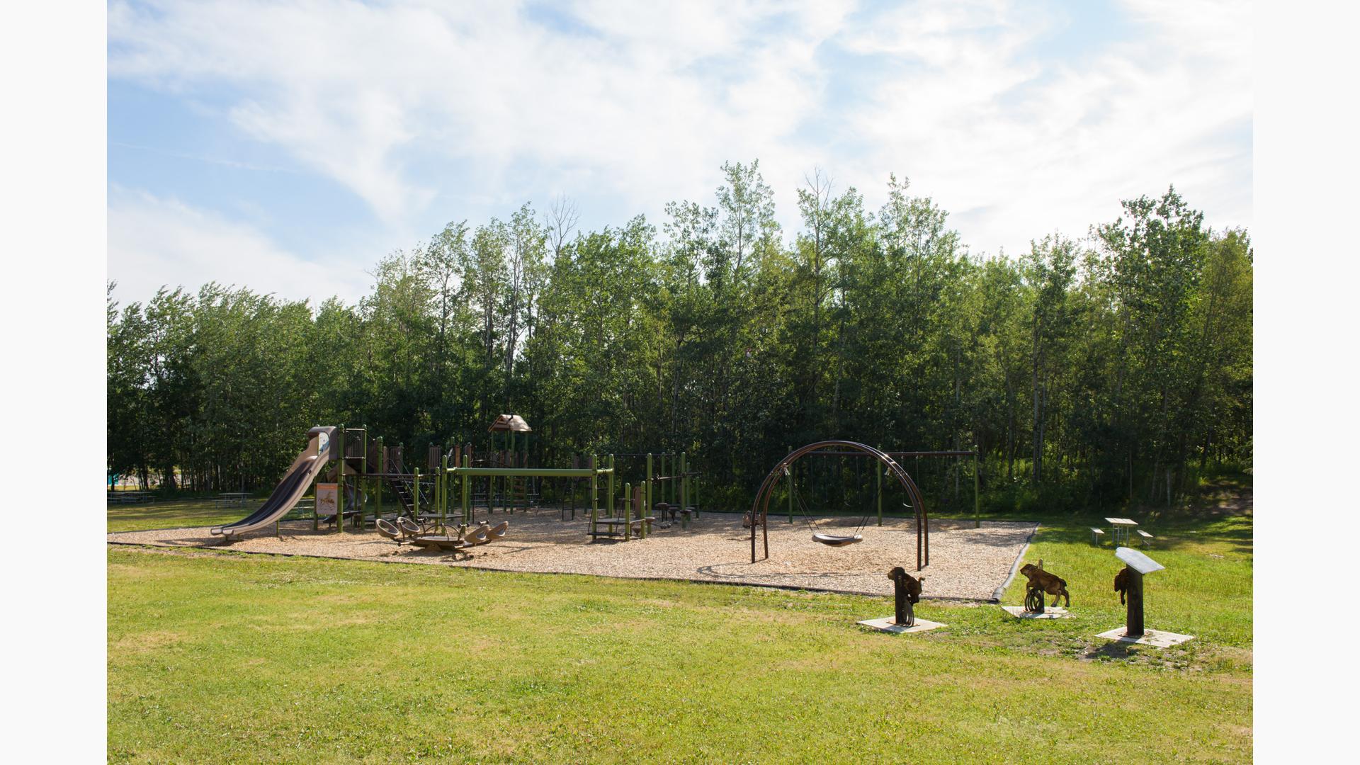 A nature-inspired playground with tall slides and swings surrounded by trees