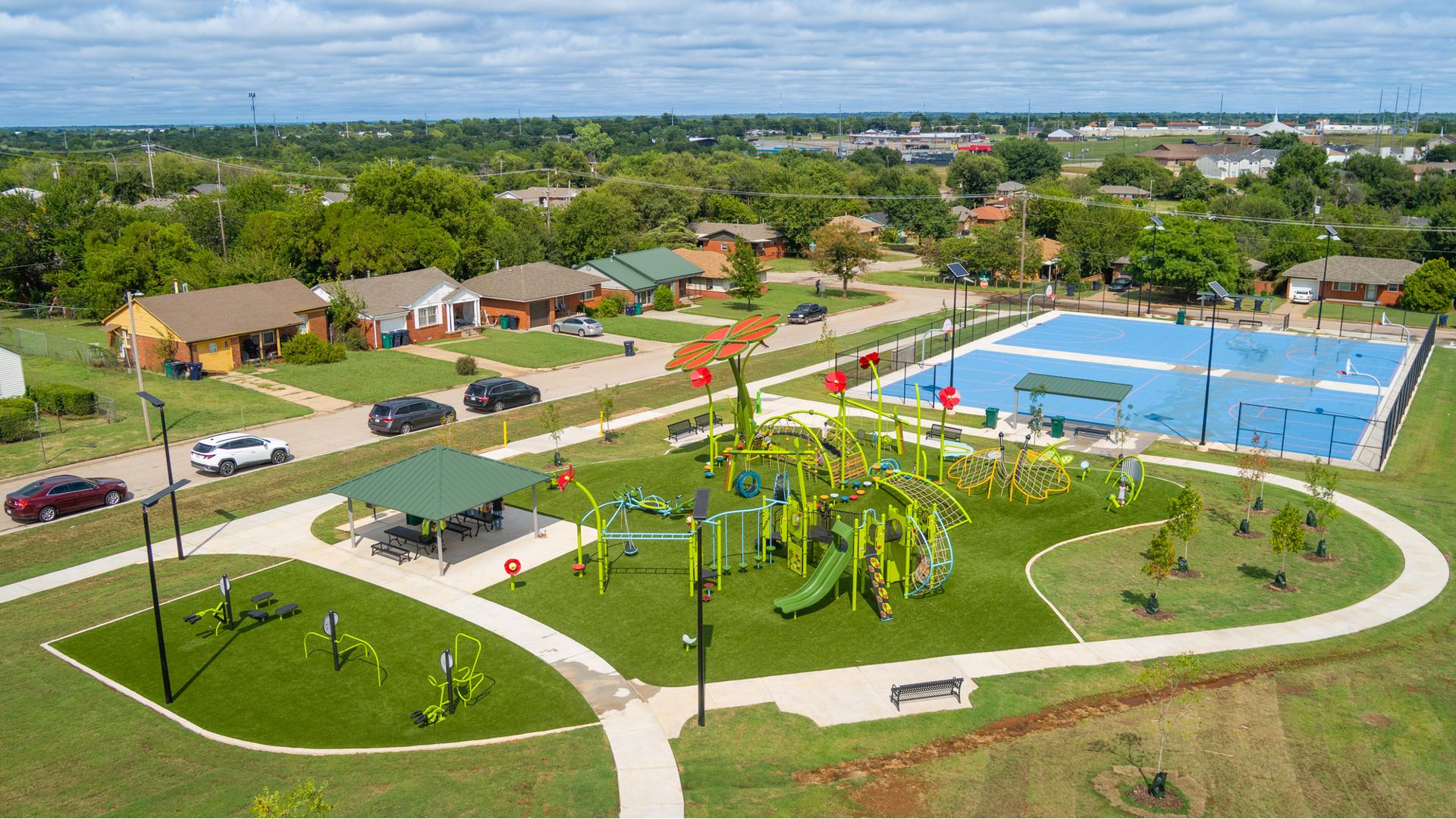 Elevated view of a neighborhood nature themed playground, outdoor work out equipment, and nearby basketball courts.