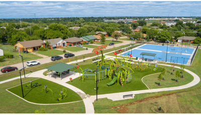 Elevated view of a neighborhood nature themed playground, outdoor work out equipment, and nearby basketball courts.