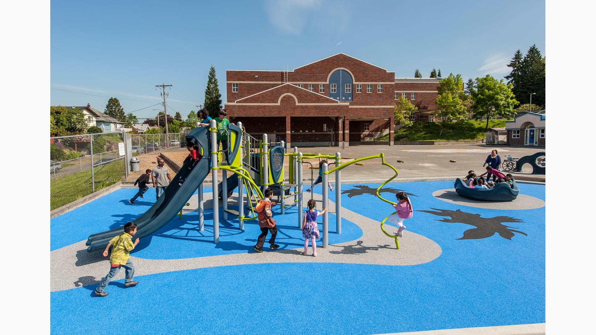 Kids at Hawthorne Elementary School playing on playground. Elementary school building in the background and surrounding neighborhood in the background.